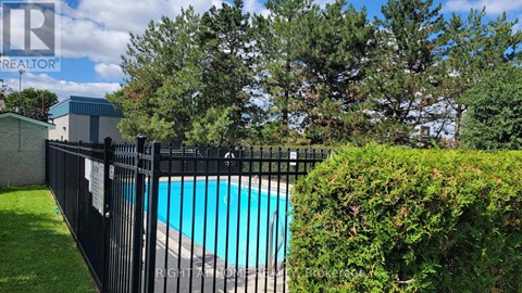 A pool surrounded by a black fence and green bushes.