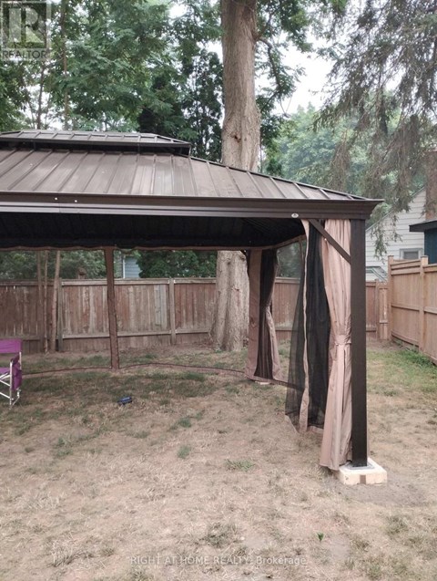 A gazebo with a brown roof is surrounded by a wooden fence.