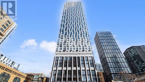 A tall building with many windows stands in front of other buildings.