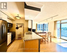 A kitchen with a refrigerator, sink, and a dining table with chairs.