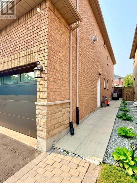 A brick house with a grey garage door and a concrete walkway.