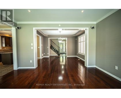 A spacious room with wood flooring and a staircase leading to the second floor.
