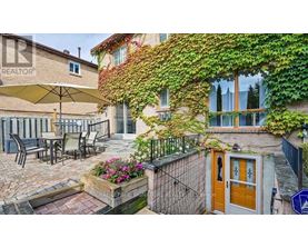 A patio with a table and chairs is surrounded by a wall covered in green vines.