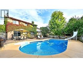 A pool in a backyard with a house and trees in the background.