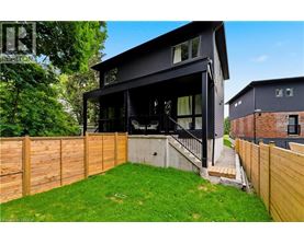 A modern black house with a wooden fence and green lawn.