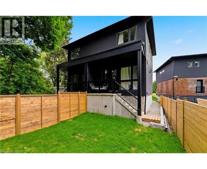 A modern black house with a wooden fence and green lawn.