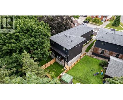 A modern house with a black roof is surrounded by a green lawn and trees.