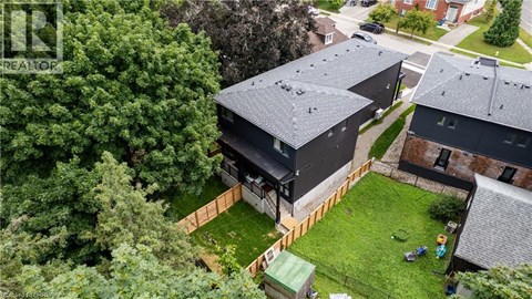 A modern house with a black roof is surrounded by a green lawn and trees.