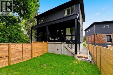 A modern black house with a wooden fence and green lawn.