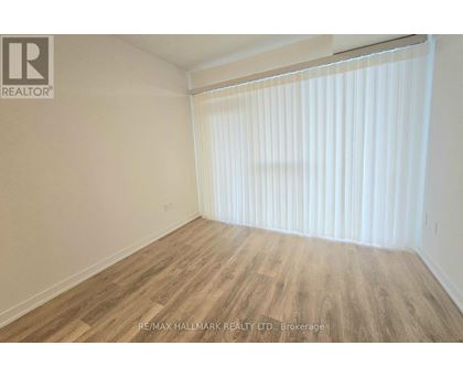 A room with wooden flooring and white blinds on the window.