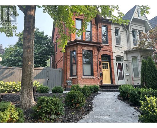 A brick house with a yellow door and a tree in front.