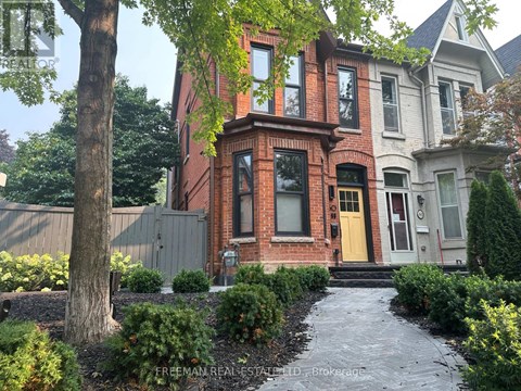 A brick house with a yellow door and a tree in front.