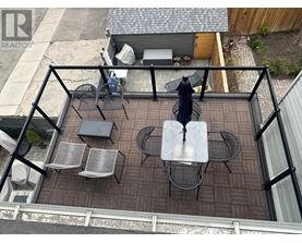 A patio with a table and chairs is surrounded by a black railing.