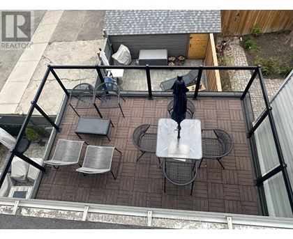 A patio with a table and chairs is surrounded by a black railing.
