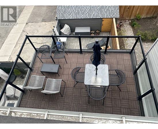 A patio with a table and chairs is surrounded by a black railing.