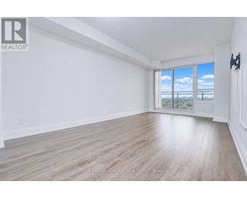 A spacious room with wooden flooring and a large window overlooking the city.