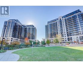 Two modern apartment buildings with a grassy area in front.