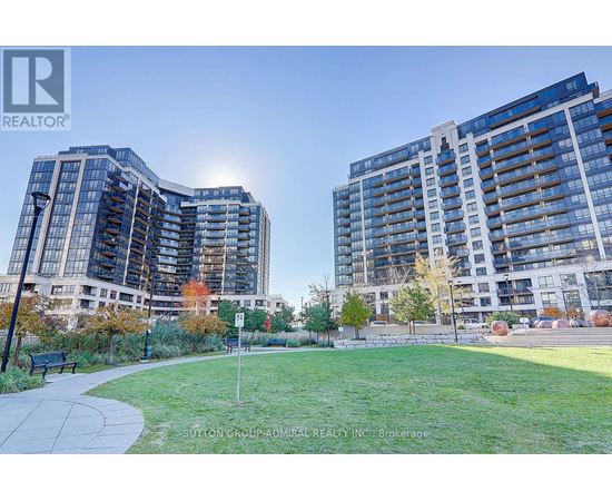 Two modern apartment buildings with a grassy area in front.