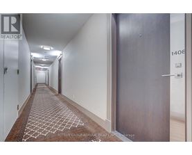A hallway with a rug on the floor and doors on either side.