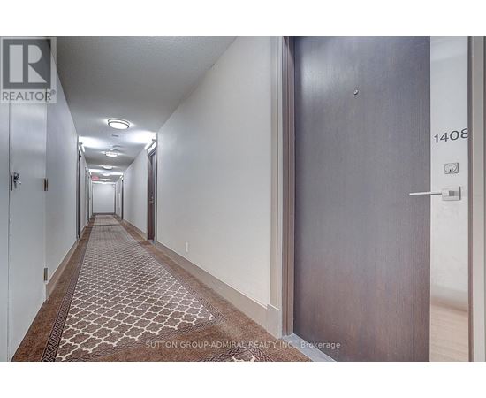 A hallway with a rug on the floor and doors on either side.