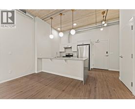 A spacious room with a kitchenette and wooden flooring.