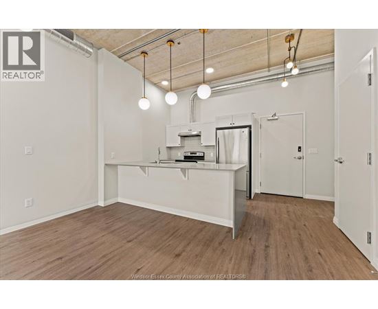 A spacious room with a kitchenette and wooden flooring.