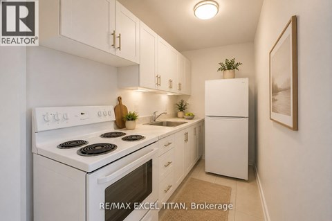 A white kitchen with a stove top oven and a refrigerator.