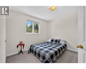 A bedroom with a bed, a small table, and a window.
