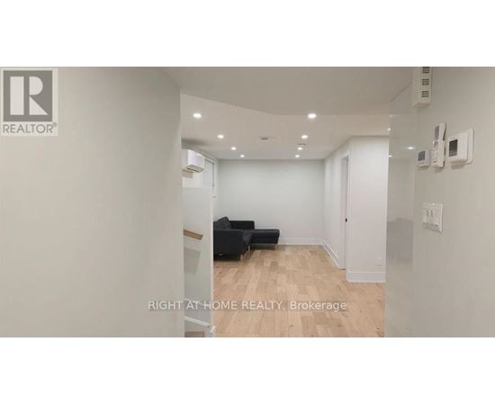 A spacious room with a black sofa and wooden flooring.