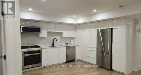 A modern kitchen with white cabinets and stainless steel appliances.