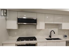 A modern kitchen with a stove top oven and a microwave above it.