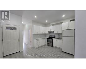 A white kitchen with a white door and white cabinets.