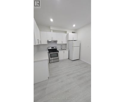 A white kitchen with a stove top oven and a refrigerator.