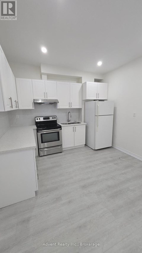 A white kitchen with a stove top oven and a refrigerator.