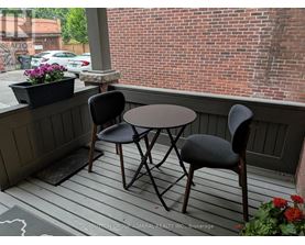 A small table and two chairs are on a porch.