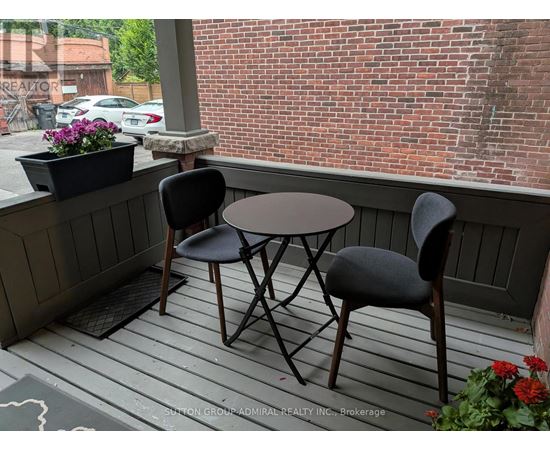 A small table and two chairs are on a porch.