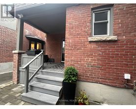 A red brick building with a grey staircase leading to a door.