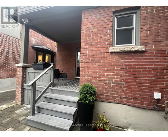 A red brick building with a grey staircase leading to a door.