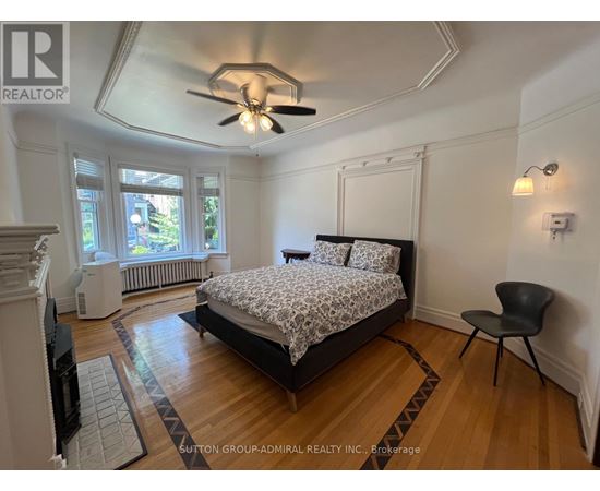 A bedroom with a bed, chair, and ceiling fan.