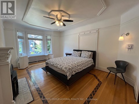 A bedroom with a bed, chair, and ceiling fan.
