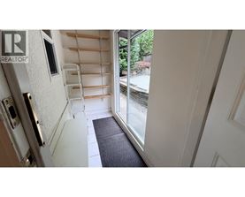 A hallway with a black mat on the floor leading to a glass door.