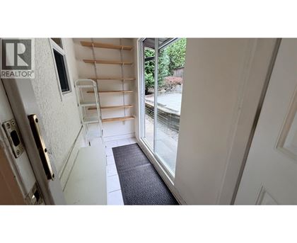 A hallway with a black mat on the floor leading to a glass door.