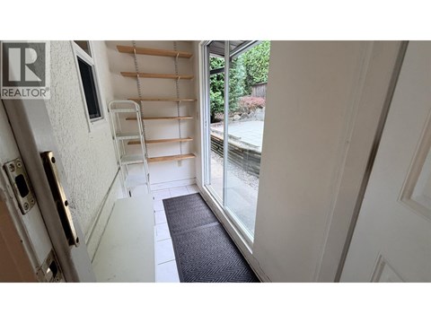A hallway with a black mat on the floor leading to a glass door.