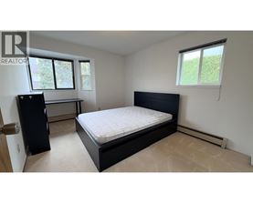 A bedroom with a bed, dresser, and window.