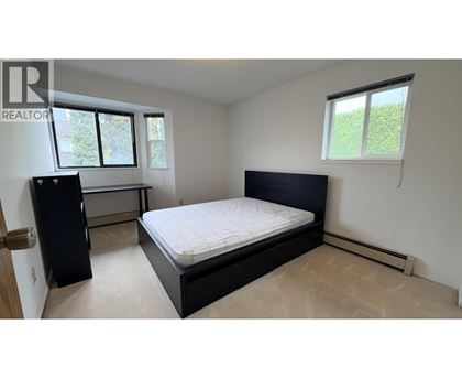 A bedroom with a bed, dresser, and window.