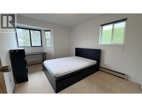 A bedroom with a bed, dresser, and window.