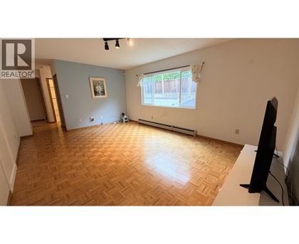 A living room with a wooden floor and a television.