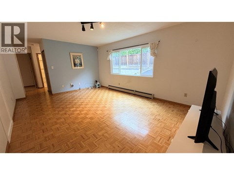 A living room with a wooden floor and a television.