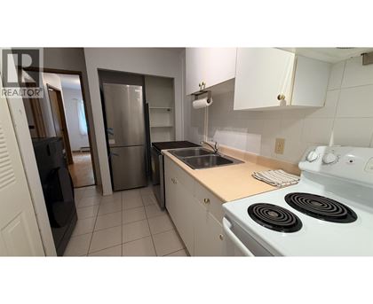 A kitchen with white appliances and a stove top oven.