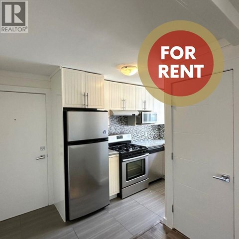 A kitchen with a refrigerator, oven, and microwave is for rent.